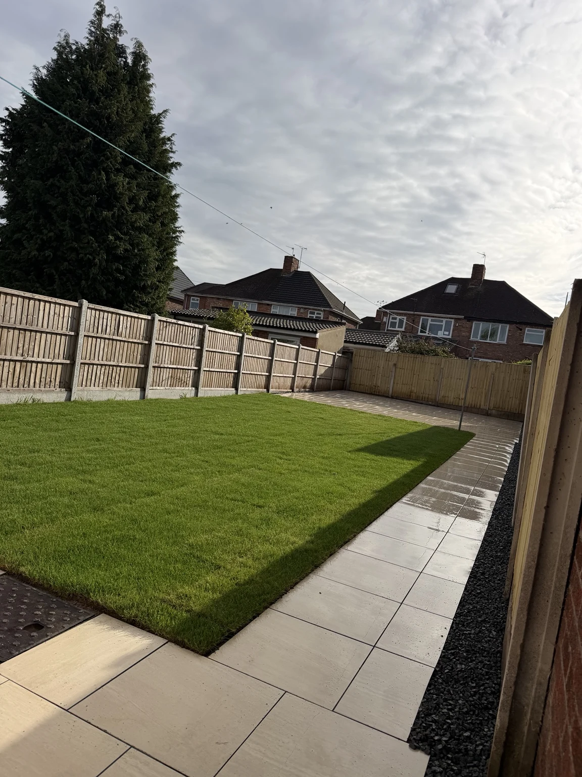 Fresh turf framed by porcelain paving and fence panels