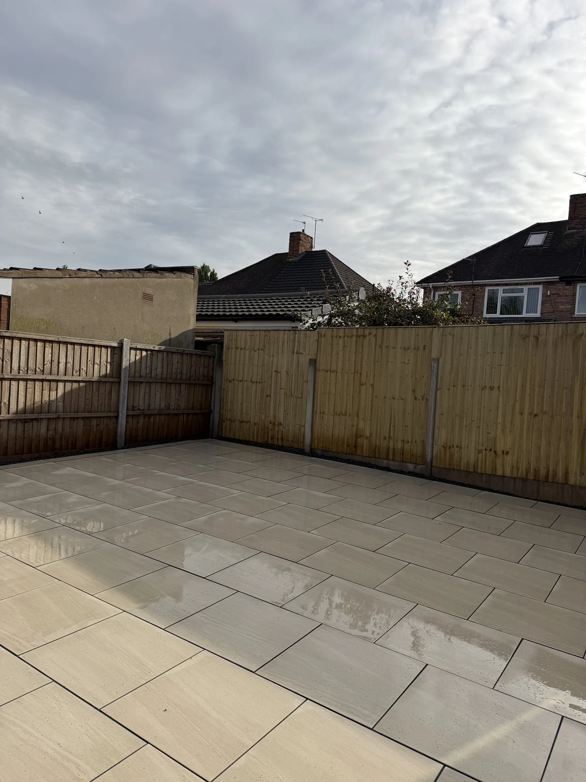 Spacious porcelain patio with new fence panels