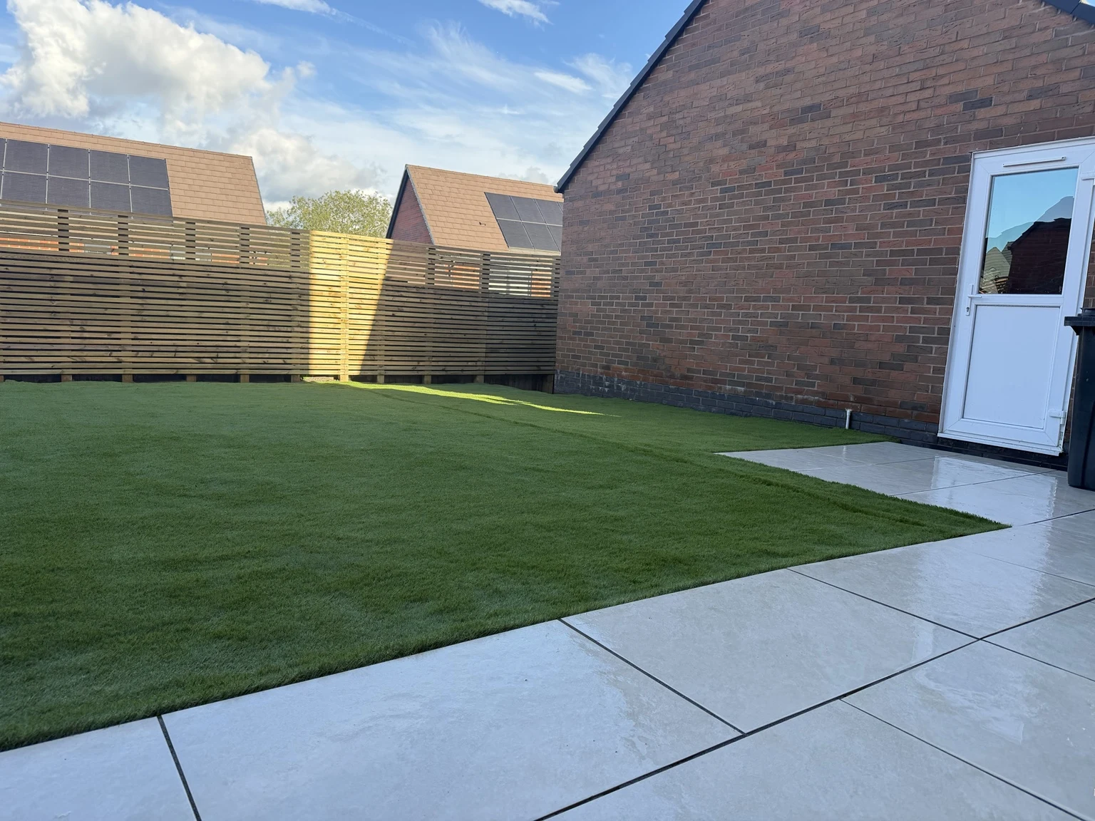Completed porcelain patio and artificial lawn framed by Venetian fencing