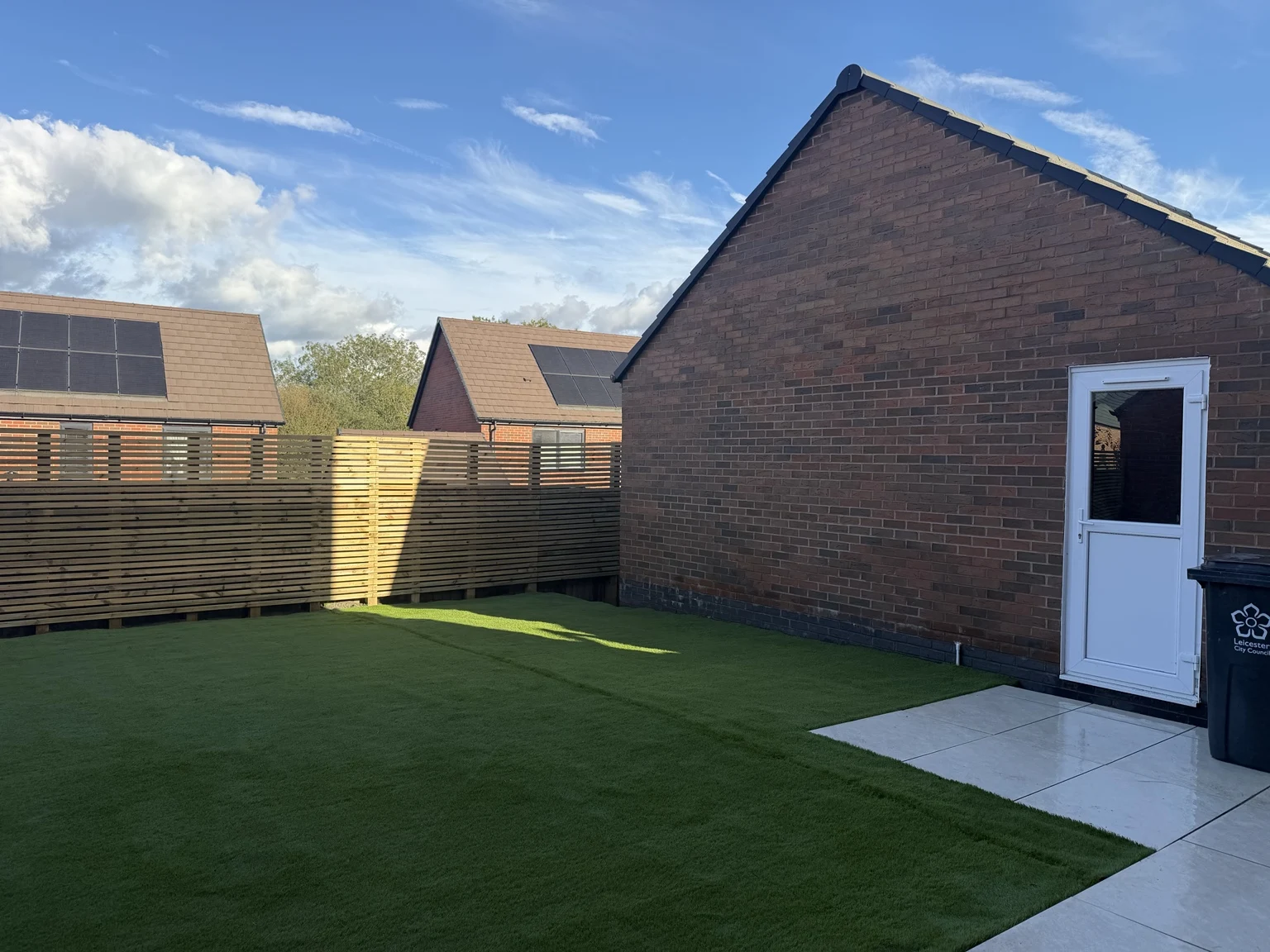 Finished artificial lawn and porcelain paving beside the house