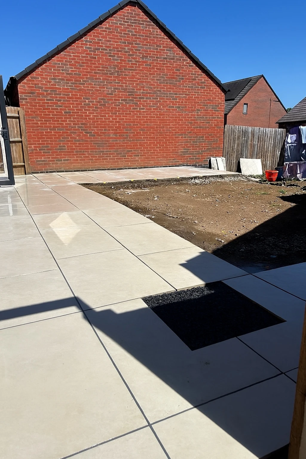 Earlier view of the installed porcelain patio with the central area awaiting turf